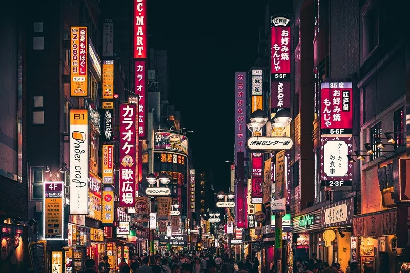Rue animée de Tokyo la nuit, idéale pour une immersion linguistique et culturelle japonaise
